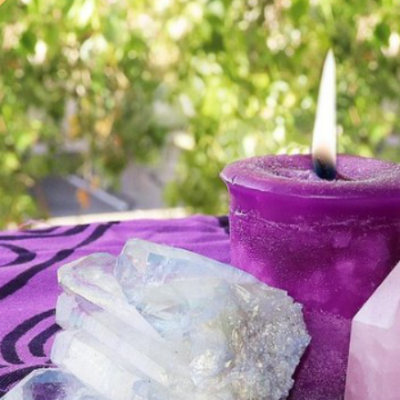 A purple candle and crystals on a table in the garden
